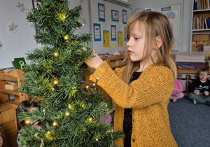 Dziewczynka zawiesza ozdobę na choince
