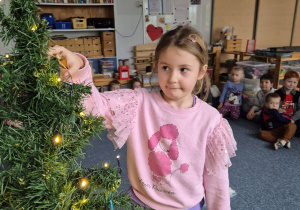 Dziewczynka zawiesza ozdobę na choince