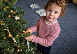 Dziewczynka zawiesza ozdobę na choince