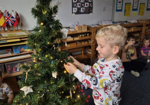 Chłopiec wiesza ozdobę na choince