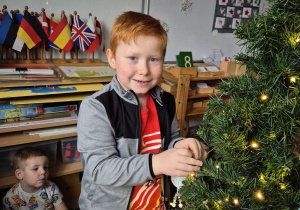 Chłopiec wiesza ozdobę na choince