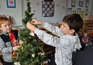 Chłopiec wiesza ozdobę na choince