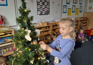 Dziewczynka zawiesza ozdobę na choince