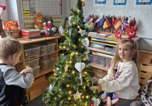 Dziewczynka zawiesza ozdobę na choince