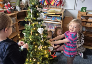 Dziewczynka zawiesza ozdobę na choince