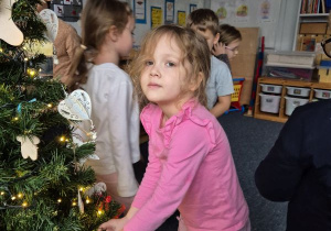 Dziewczynka zawiesza ozdobę na choince