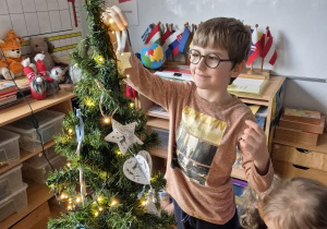 Chłopiec wiesza ozdobę na choince