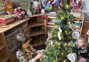 Dziewczynka zawiesza ozdobę na choince