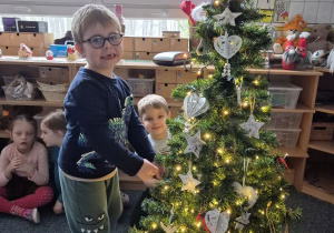 Chłopiec wiesza ozdobę na choince