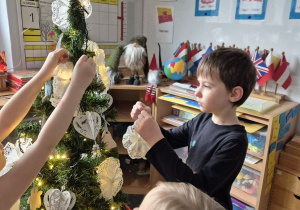 Chłopiec wiesza ozdobę na choince