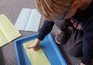 Chłopiec wykonuje pracę plastyczną z choinką