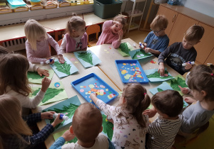 Dzieci ozdabiają choinki odbite na połowie kartki papieru