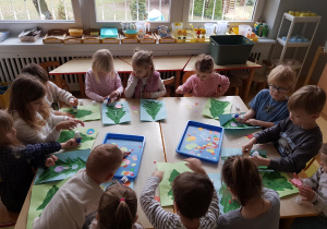 Dzieci ozdabiają choinki odbite na połowie kartki papieru