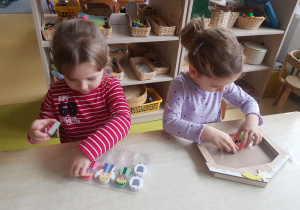 Dziewczynki układają figurki z szopki bożonarodzeniowej