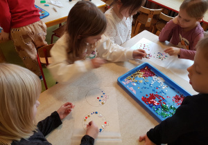 Dzieci wykonują bombki z wykorzystaniem cekinów