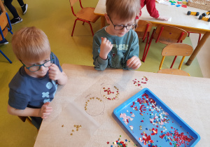 Dzieci wykonują bombki z wykorzystaniem cekinów