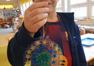 Chłopiec prezentuje własnoręcznie wykonaną bombkę