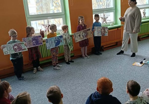 Dzieci stoją obok siebie, w dłoniach trzymają duże banknoty o różnych nominałach