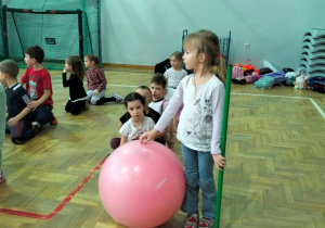 dziewczynka przygotowuje się do ćwiczenia w toczeniu piłki