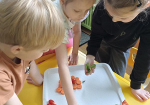 Dzieci układają pokrojone warzywa na tacy