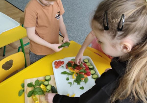 Dzieci układają warzywa na tacy
