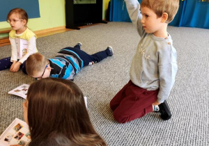 Dzieci oglądają książeczki, chłopiec podnosi rękę do góry