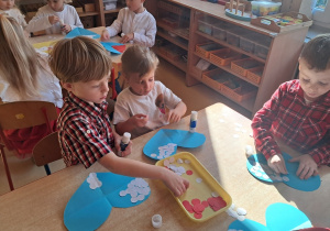 Dzieci ozdabiają serce biało - czerwonymi barwami