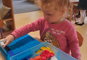 Dziewczynka układa obrazek z kolorowych elementów