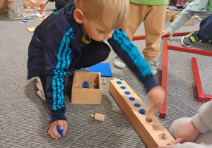 Chłopiec podczas działań z kolorowymi walcami