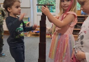 Dzieci układają wieżę z brązowych schodów