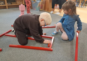 Dzieci działają z czerwonymi sztangami