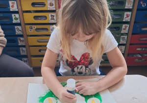 Dziewczynka wykleja świece na wieńcu adwentowycm