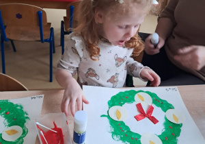 Dziewczynka podczas pracy przy wieńcu adwentowym