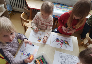 Dzieci siedzą przy stole i wykonują królewskie prace plastyczne
