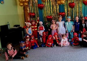 Dzieci pozują do zdjęcia ubrane w stroje karnawałowe na tle dekoracji z balonów