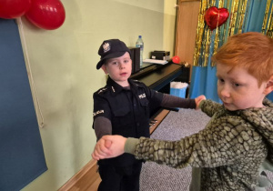 Chłopiec przebrany za policjanta tańczy z chłopcem przebranym za dinozaura