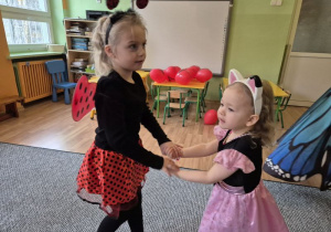 Dziewczynka w stroju biedronki tańczy z dziewczynką w stroju Pandusia