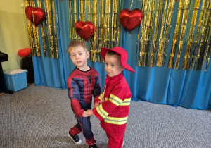 Chłopiec przebrany za Spidermana tańczy z chłopcem przebranym za strażaka