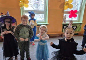 Dzieci w strojach: czarownicy, dinozaura, Elzy i kotka stoją obok siebie podczas tańca