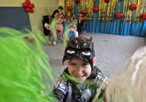 Chłopiec pozuje do zdjęcia machając trzymanymi w dłoniach pomponami