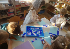 Dzieci przygotowują tło do pracy plastycznej