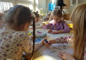 Dzieci kolorują obrazek z pingwinem