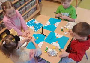 Dzieci przy stoliku podczas wykonywania pracy plastycznej o tematyce zimowej pt. "Bałwanki"