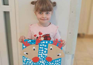 Dziewczynka trzyma w dłoniach swoją pracę plastyczną przedstawiającą renifery