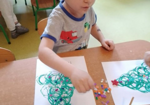 Chłopiec podczas wykonywania pracy plastycznej przedstawiającej świąteczną choinkę