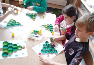 Dzieci przy stoliku w czasie wykonywania pracy plastycznej pt. "Choinka"