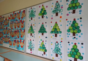 Wystawa prac dzieci na tablicy w holu przedszkola o tematyce świątecznej