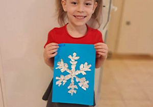 Tosia pozuje do zdjęcia z wykonaną przez siebie pracę plastyczną pt. "Śnieżynka"