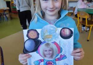 Dziewczynka prezentuje pracę plastyczną: ,,Ja w kosmosie".