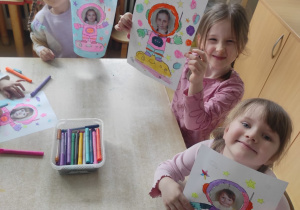 Dziewczynki prezentują pracę plastyczną dotyczącą lotu w kosmos.